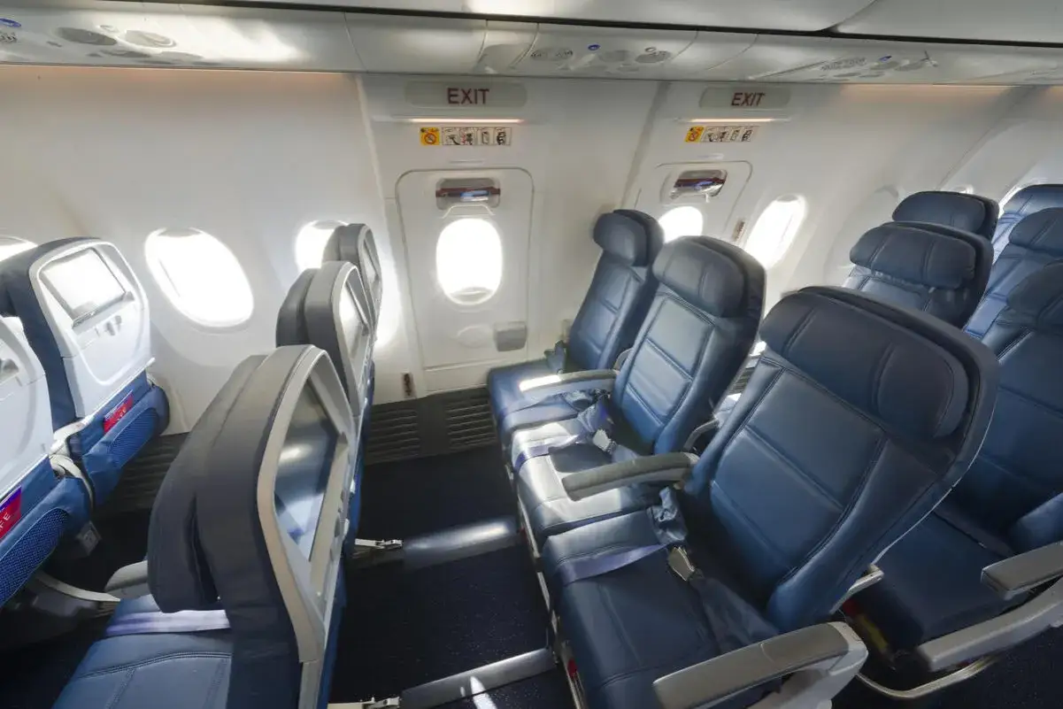 Wnętrze samolotu Boeing 737-900 z rzędami niebieskich foteli i oknami.