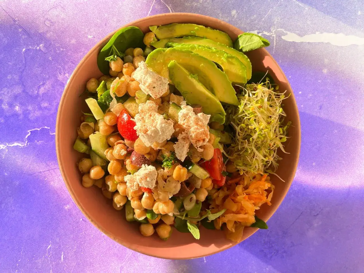 Salade colorée avec pois chiches, avocat, concombre, tomates et germes, une alimentation riche en protéines pour un repas sain et savoureux.