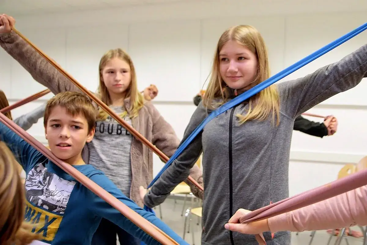 Kinder üben mit bunten Bändern, eine spielerische Art, **lernen mit spass** zu verbinden.