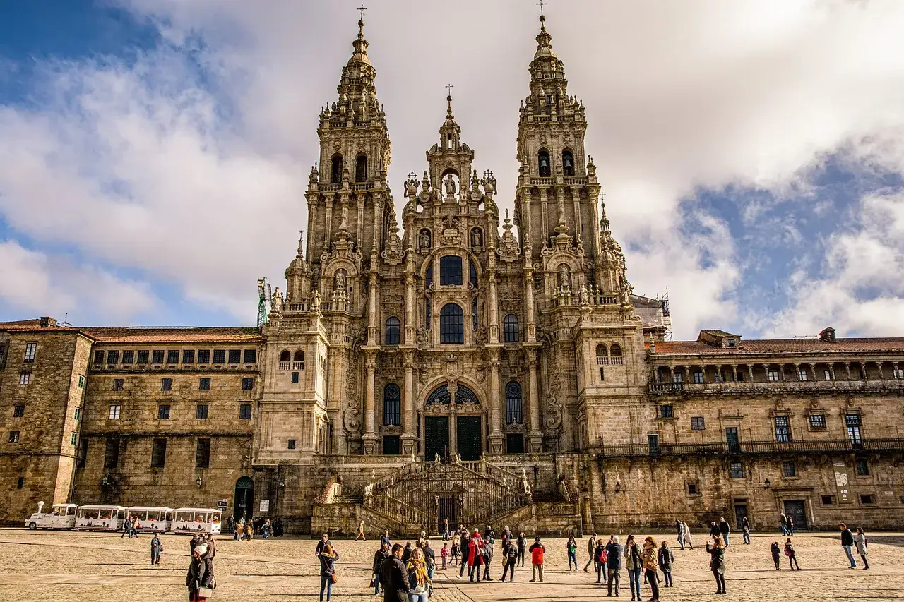 Impresionante fachada de la catedral románica España, con sus torres y escalinatas. Gente pasea por la plaza.