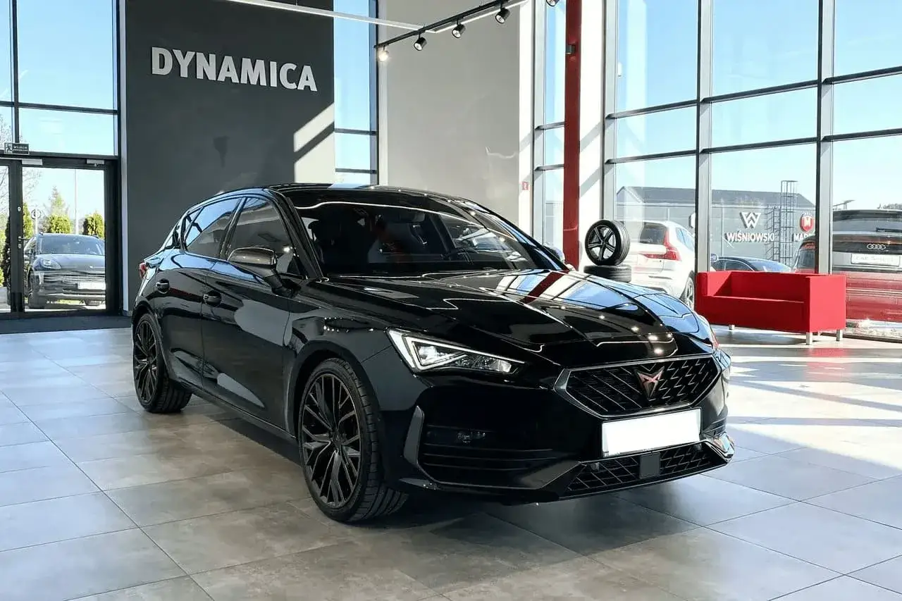 Czarny, sportowy coupe z przyciemnianymi szybami i czarnymi felgami stoi w salonie samochodowym.
