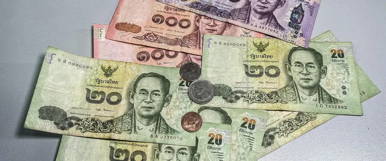 Thai Baht-Scheine und M&uuml;nzen liegen auf einem Tisch. Bereit, Thailand Geld zu wechseln.