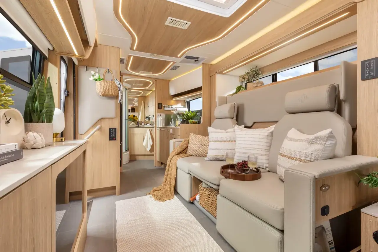 Intérieur d'un camping-car luxueux avec un salon confortable, des coussins douillets et un lit pavillon discret.