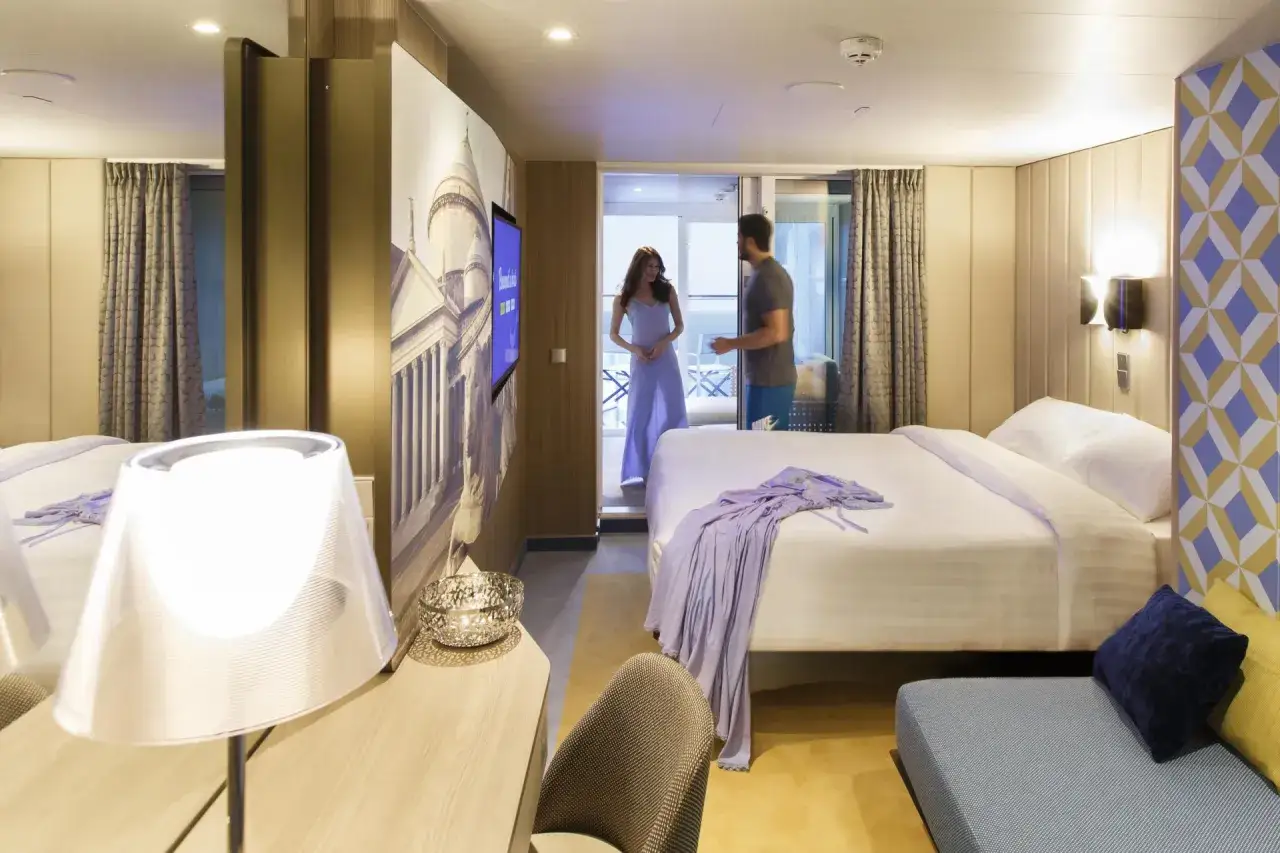 Coppia in una moderna cabina interna di Costa Crociere. Letto matrimoniale, decorazioni artistiche e un balcone invitano al relax.