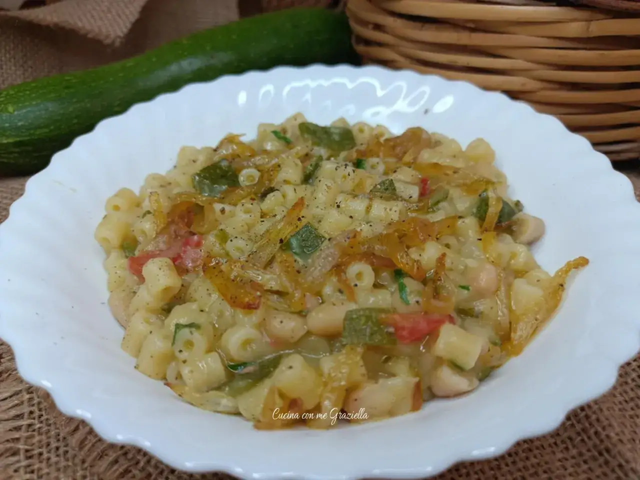 Un piatto invitante di pasta e zucchine alla pugliese, con fagioli e pomodoro, condito con erbe aromatiche.