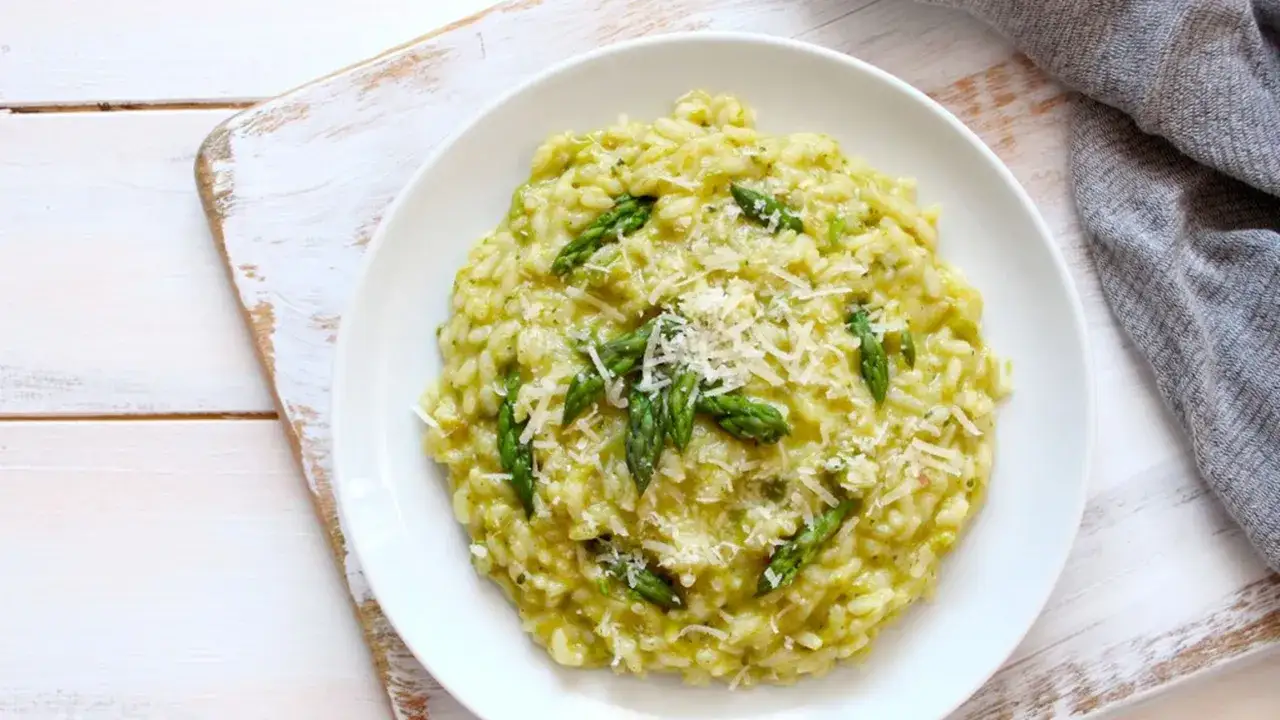 Risotto cremoso con asparagi freschi e robiola, guarnito con parmigiano grattugiato.