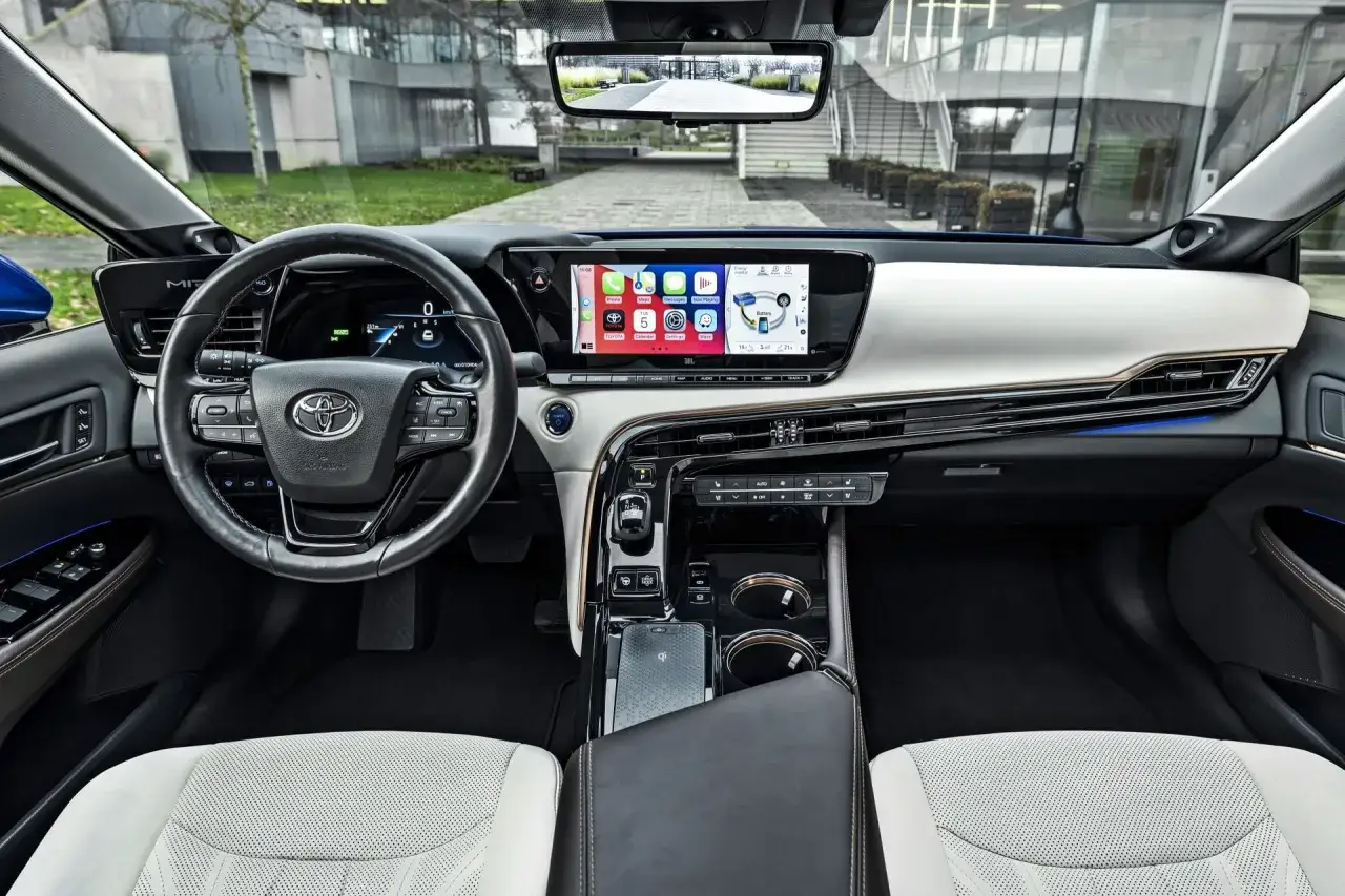 Wnętrze Toyoty Mirai. Nowoczesny kokpit z dużym ekranem multimedialnym i cyfrowymi zegarami. Sprawdź aktualną toyota mirai cena.