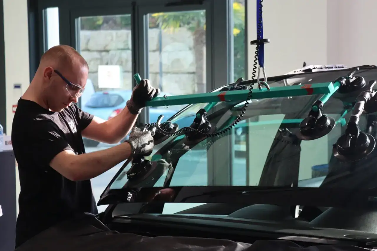 Un technicien utilise un outil de levage pour remplacer un pare-brise. Obtenez un devis pour le prix remplacement pare brise.