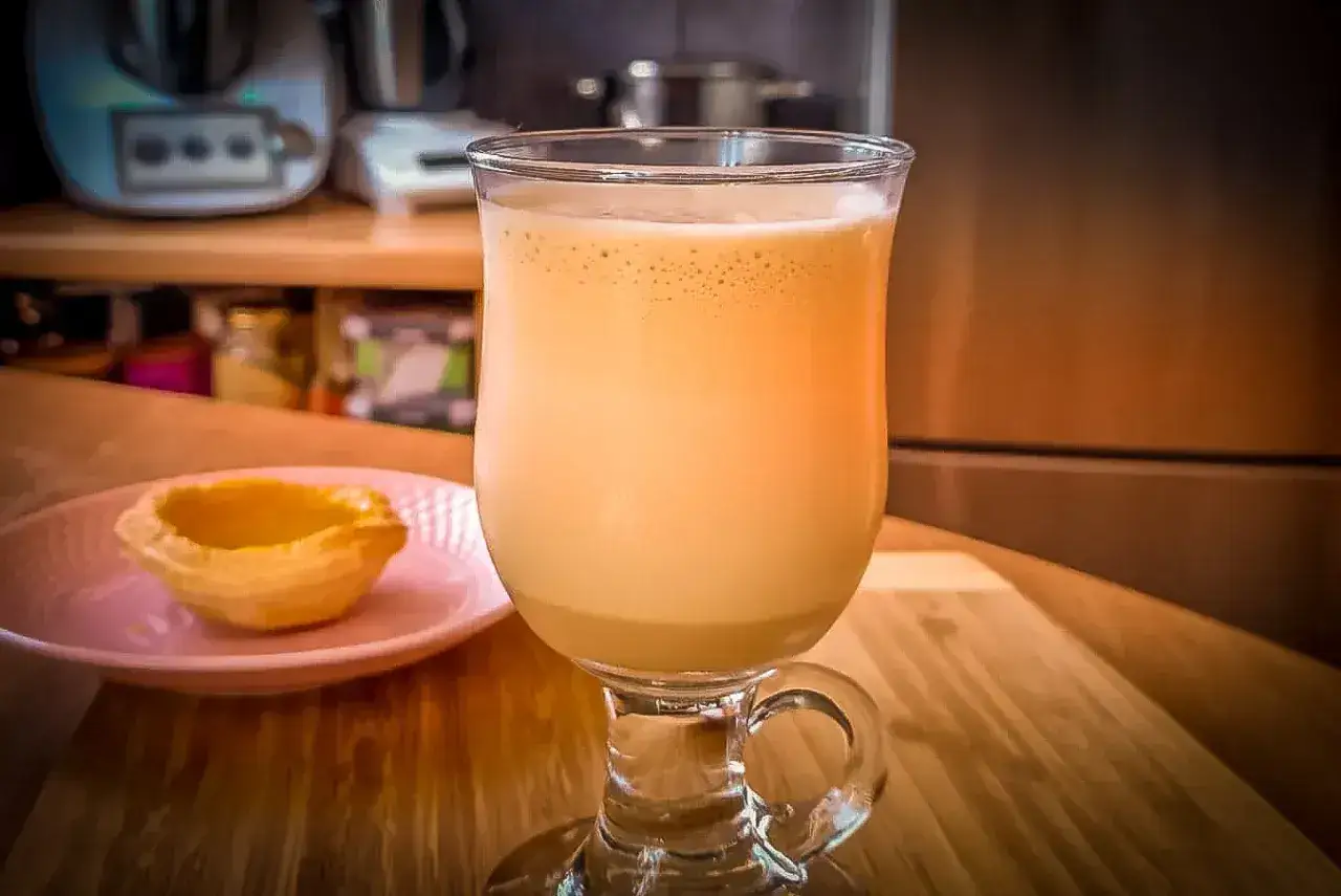 Kawa mrożona thermomix w szklance z pianką, obok pusta babeczka na talerzyku.