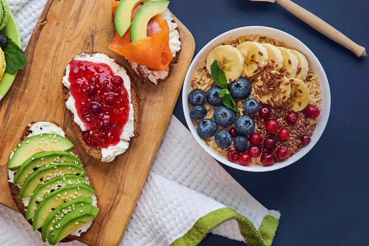 Colazione sana e gustosa: porridge con frutta e semi, toast con avocado, salmone e marmellata. Un esempio di alimentazione funzionale per iniziare la giornata con energia.