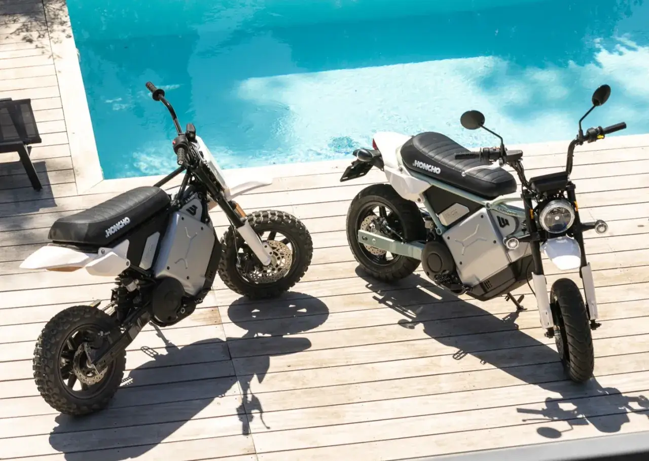 Dwa stylowe harley elektryczne HONCHO stojące na drewnianym tarasie przy basenie.