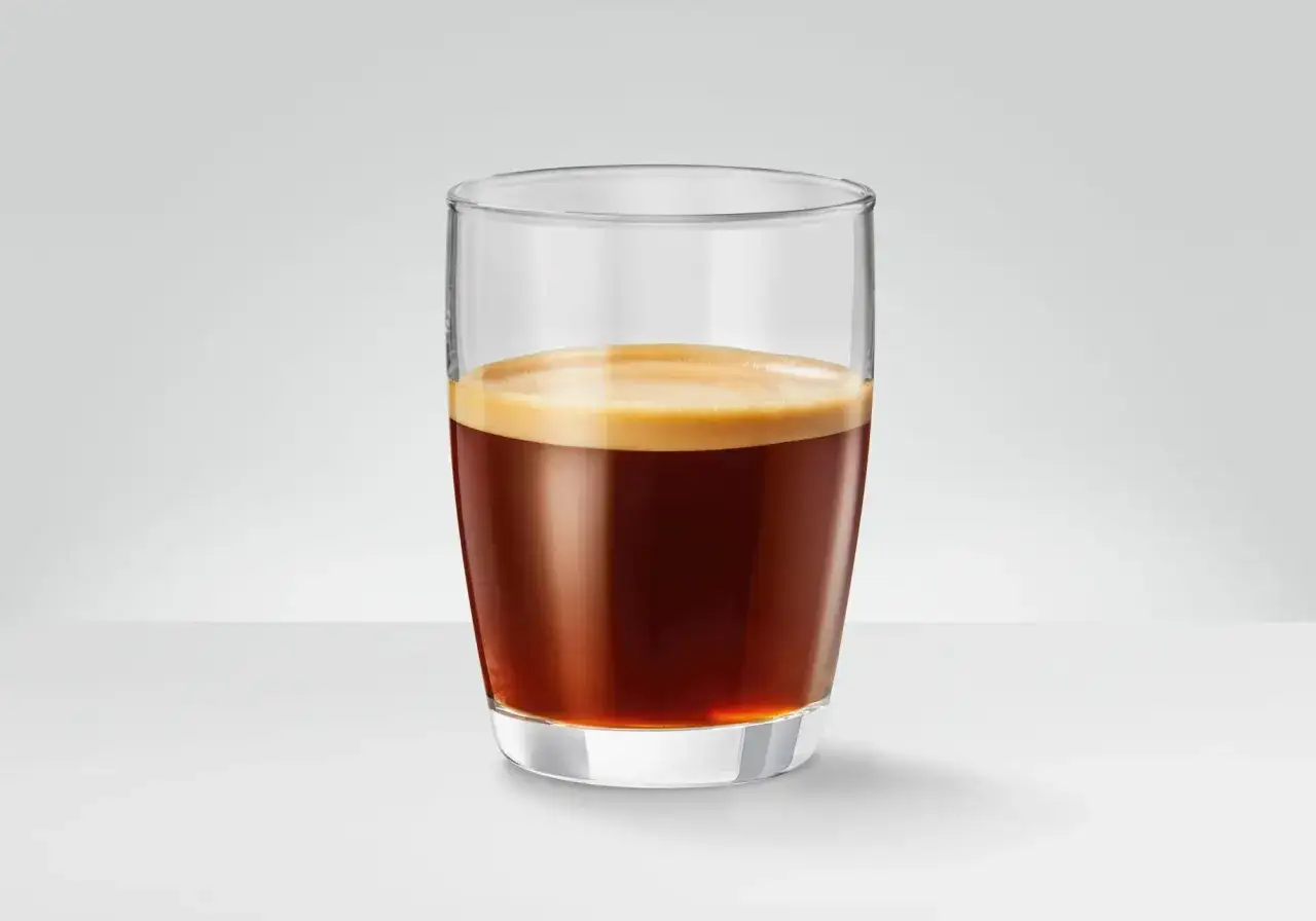 Ett glas med mörkt, aromatiskt lungo kaffe med ett krämigt skum. Perfekt för en paus.