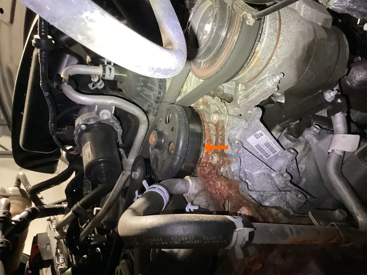 Corrosión y óxido alrededor de la bomba de agua, indicando una posible pérdida de anticongelante.
