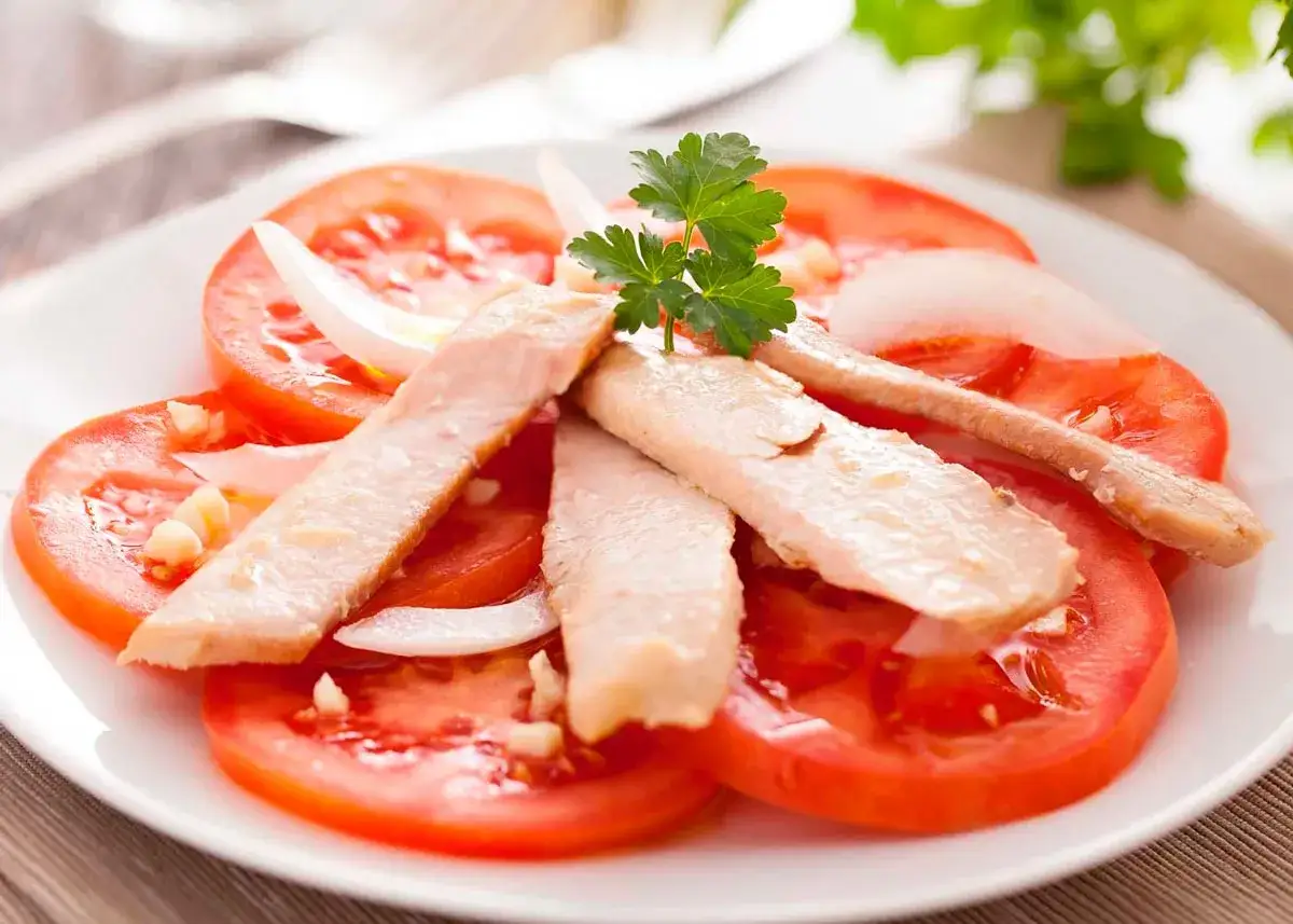 Deliciosa ensalada de ventresca con rodajas de tomate fresco, cebolla y perejil.