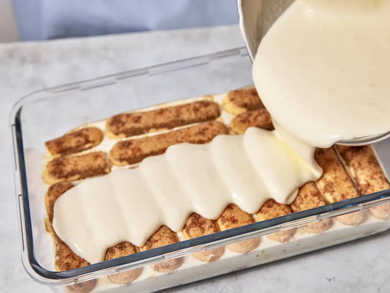 Cremige Masse wird &uuml;ber L&ouml;ffelbiskuits gegossen, ein Schritt im tiramisu rezept.