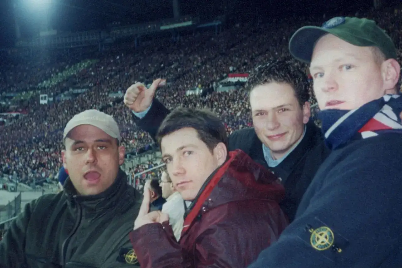 Vier Freunde, die Stone Island tragen, jubeln bei einem Fu&szlig;ballspiel.