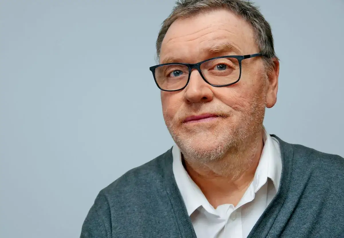 Porträt von Wolf Lotter mit Brille und grauem Cardigan.