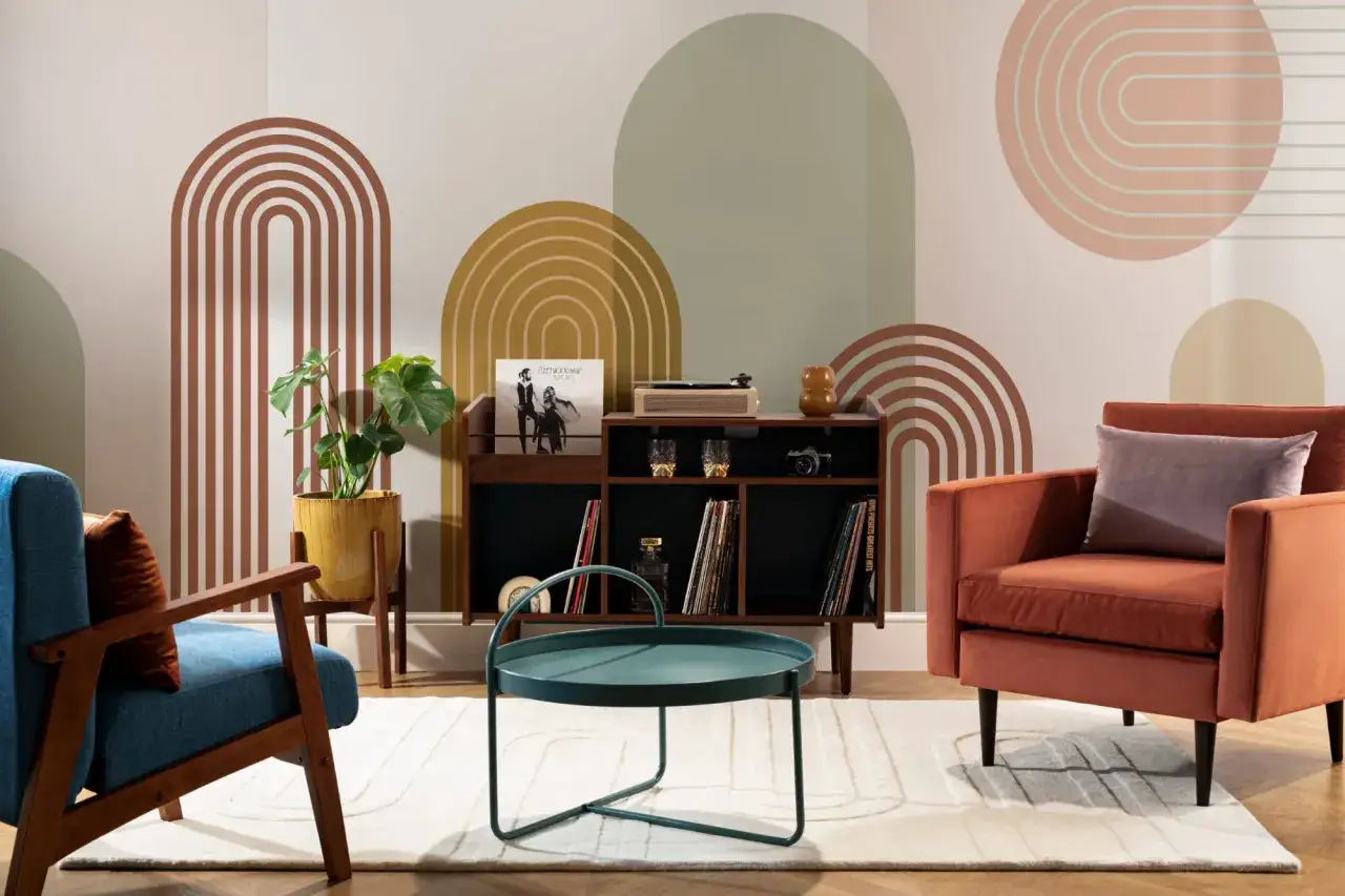 Soggiorno in stile mid century modern con poltrone colorate, mobile contenitore con giradischi e decorazioni murali ad arco.