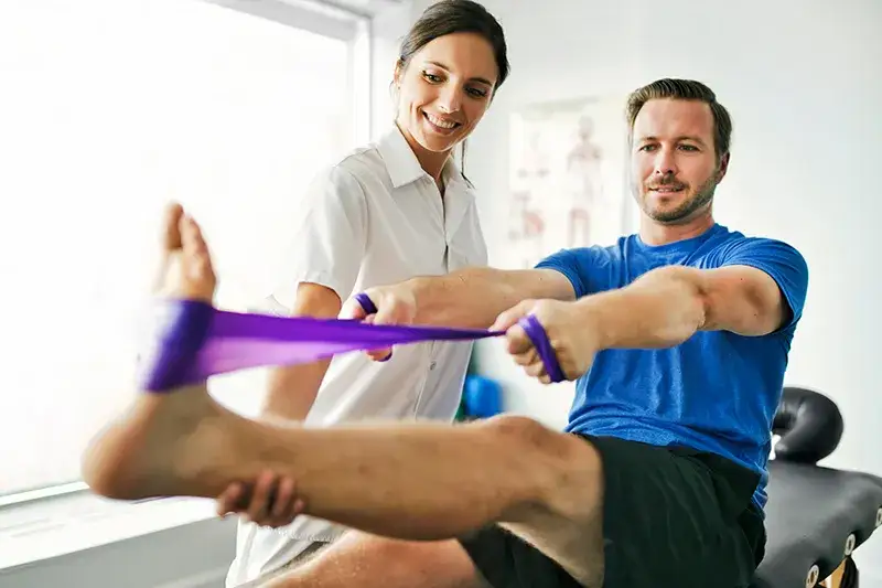 Fizjoterapeuta wykonujący ćwiczenia z pacjentem na kolano