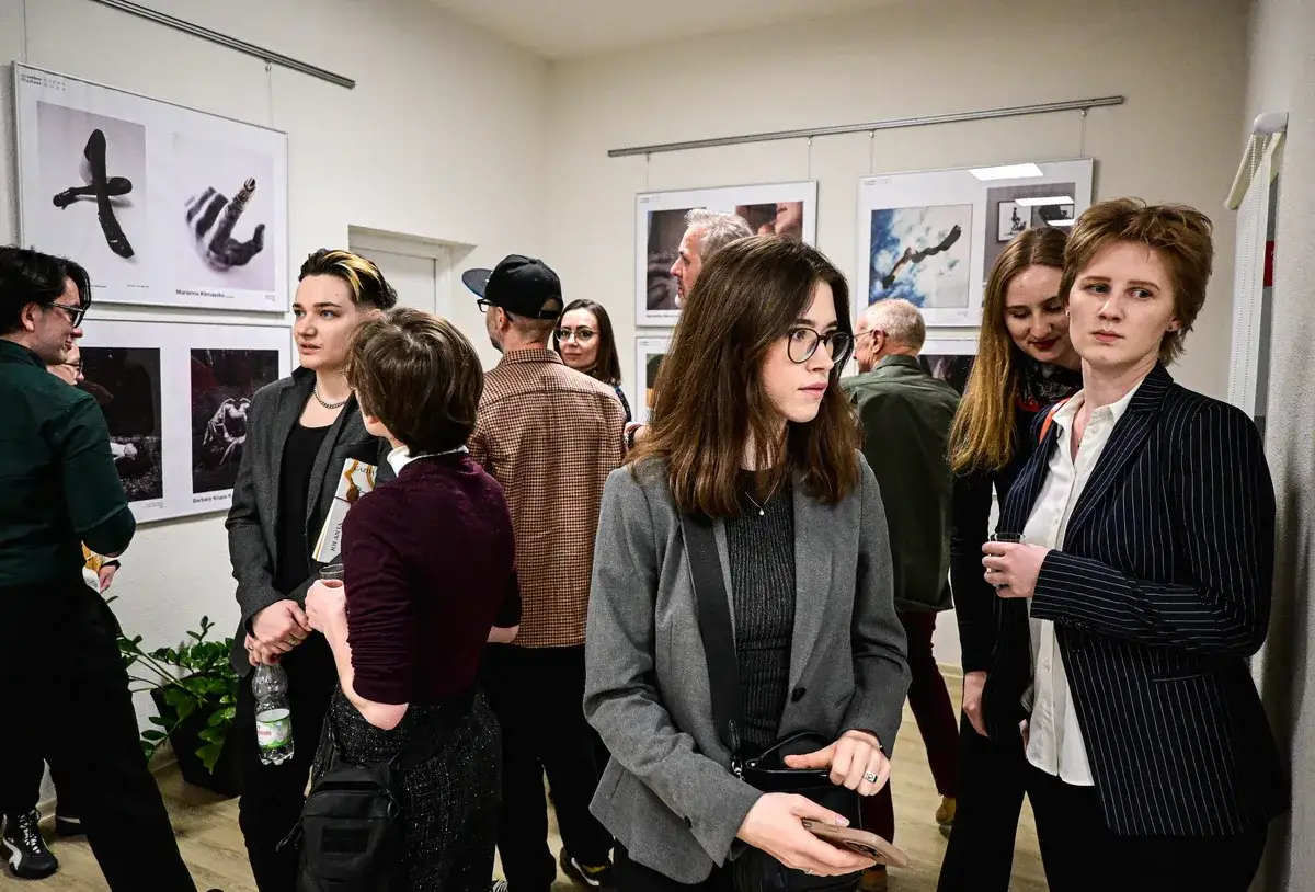 Ludzie oglądają prace na wystawie, która mogłaby być częścią międzynarodowych konkursów fotograficznych.