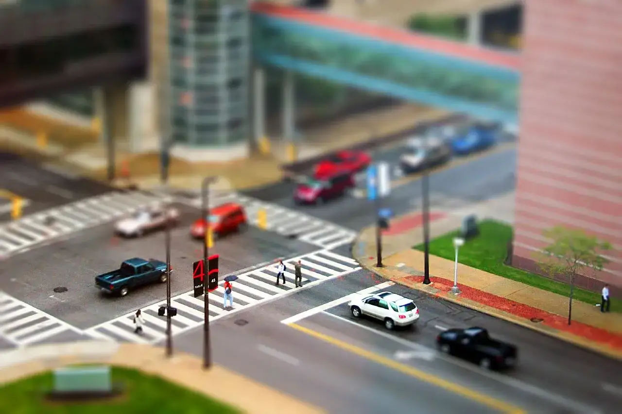 Vista a&eacute;rea de una intersecci&oacute;n urbana con coches y peatones, simulando un efecto tilt shift.