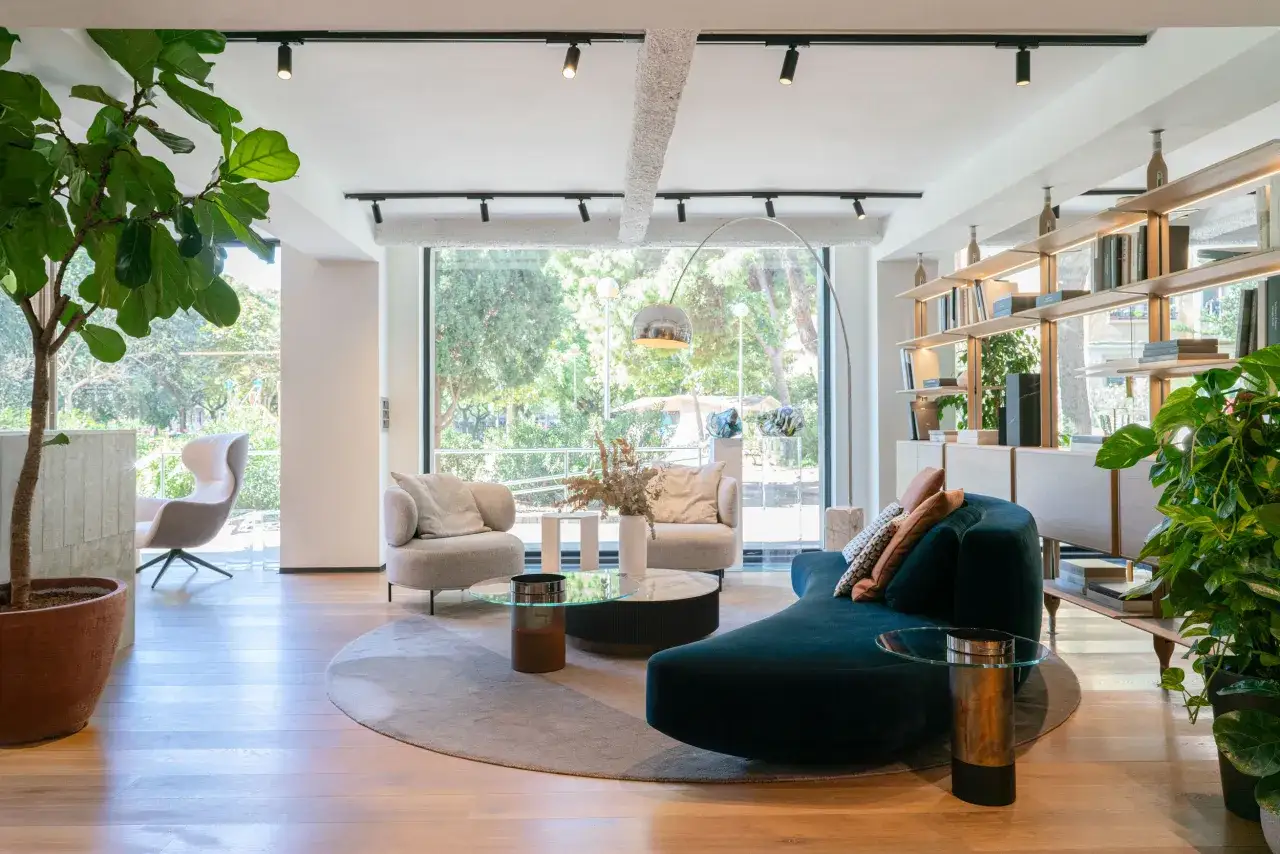 Amplia sala con grandes ventanales que ofrecen vistas al exterior, muebles modernos y estanterías.