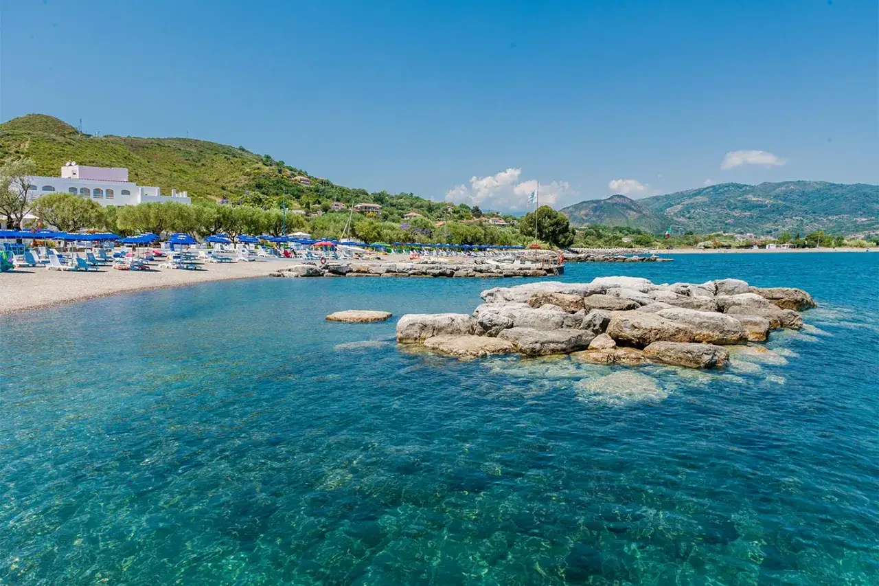 Spiaggia attrezzata con ombrelloni e lettini, mare cristallino e rocce affioranti. Un angolo da sogno tra i posti pi&ugrave; belli del Cilento mare.