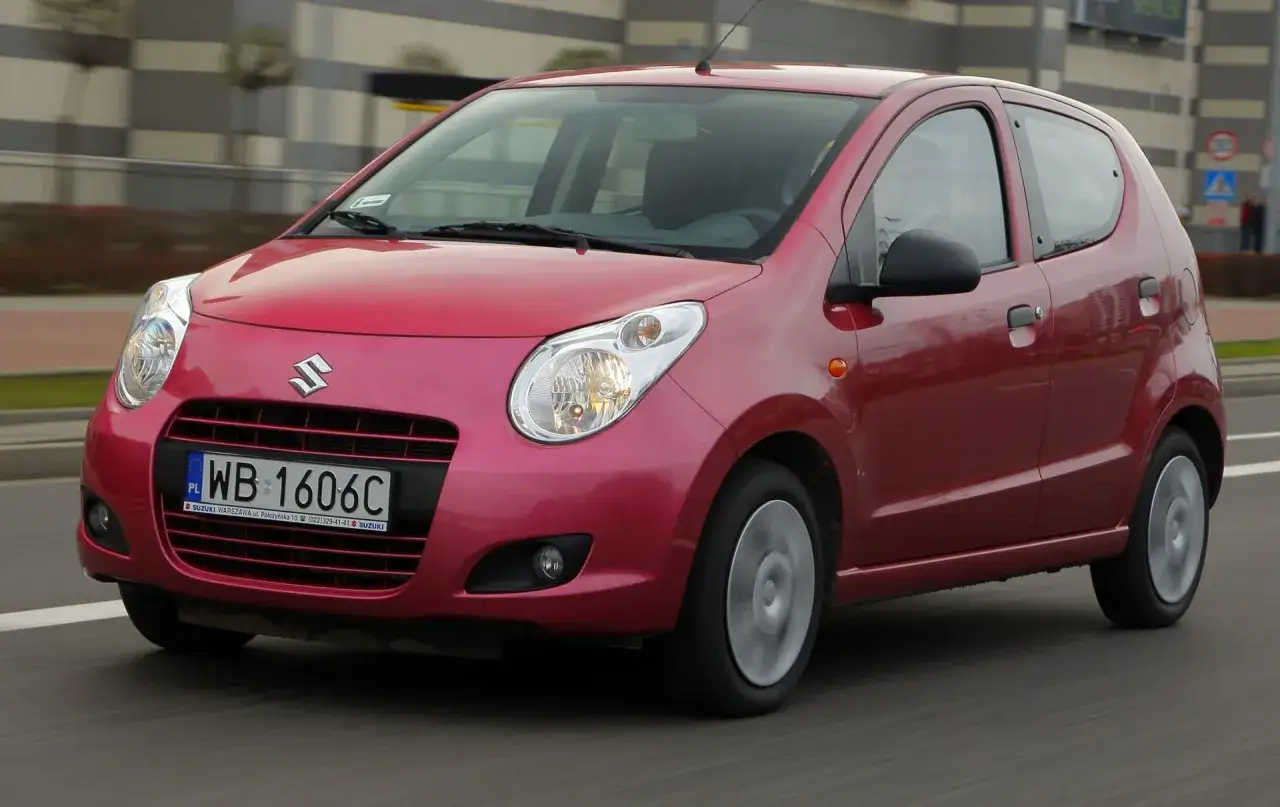 Czerwony Suzuki Alto w ruchu miejskim. Elegancki, miejski samochód z polskimi tablicami rejestracyjnymi.