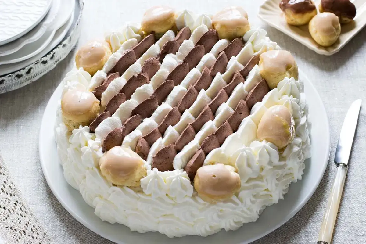 Torta Saint Honoré con panna montata, crema al cioccolato e bignè glassati. Un capolavoro di pasticceria.