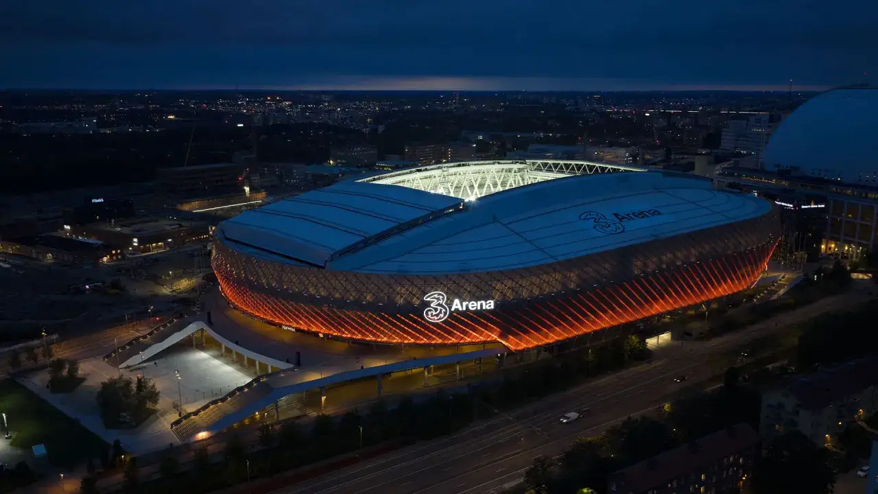 Tele2 Arena i Stockholm lyser upp natthimlen med sitt orangea sken. En ikonisk arena redo för nya evenemang.