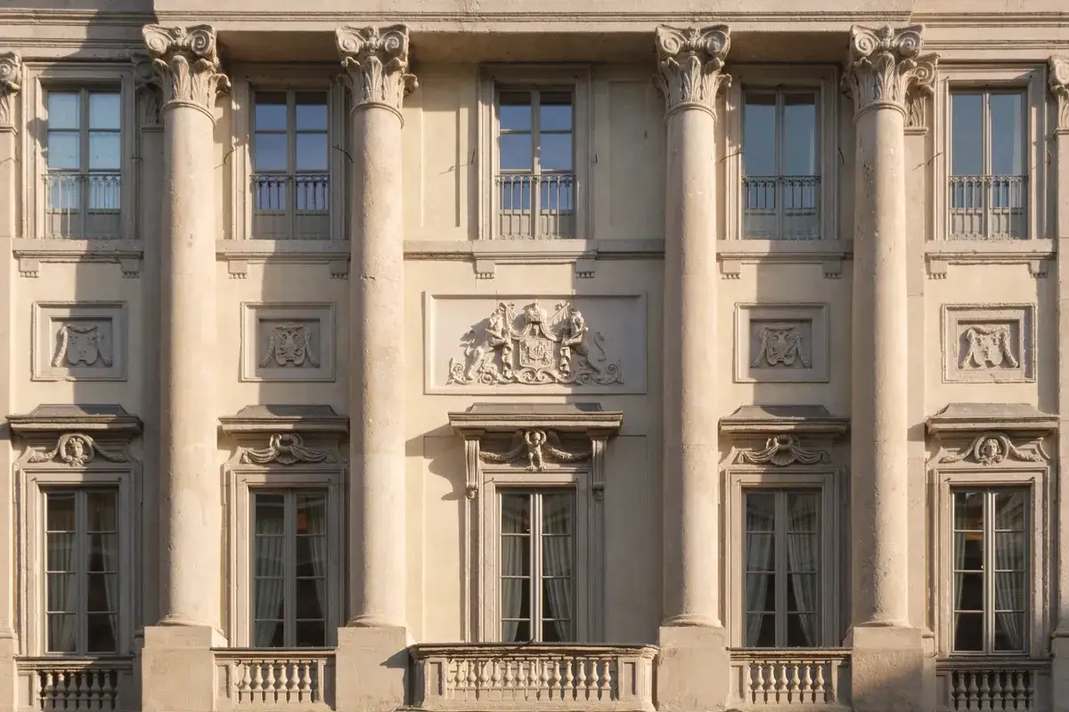Facciata del **Palazzo Belgioioso** con colonne corinzie, finestre eleganti e un bassorilievo araldico centrale.