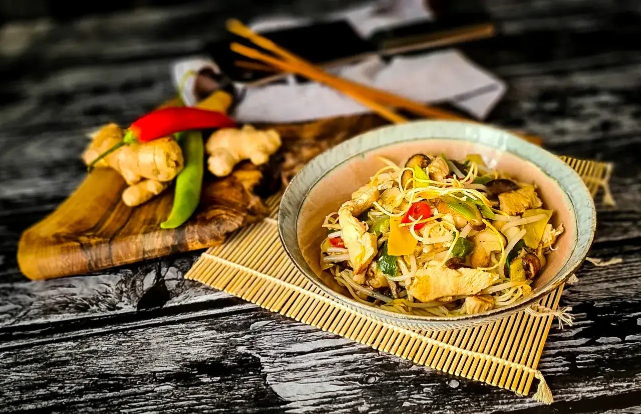 Pyszny makaron chow mein czy lo mein z kurczakiem i warzywami, podany z imbirem i papryczką chili.
