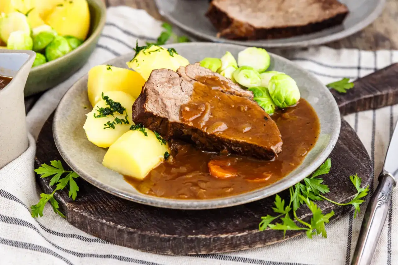 Zarter Rinderbraten im Backofen, serviert mit Kartoffeln und Rosenkohl in reichhaltiger Sauce. Ein Festmahl!