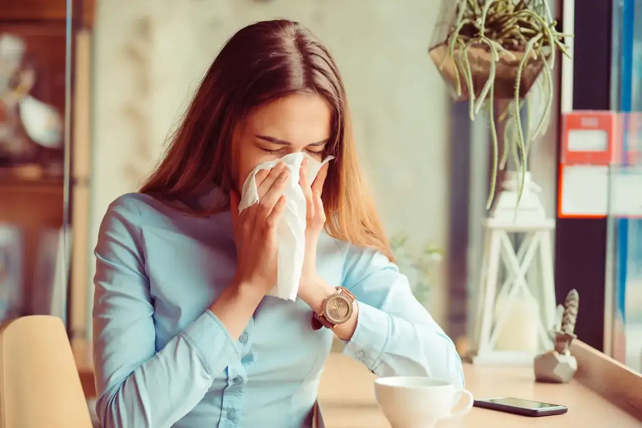 Mujer estornudando con un pañuelo, quizás porque se puede tener alergia al aire acondicionado.