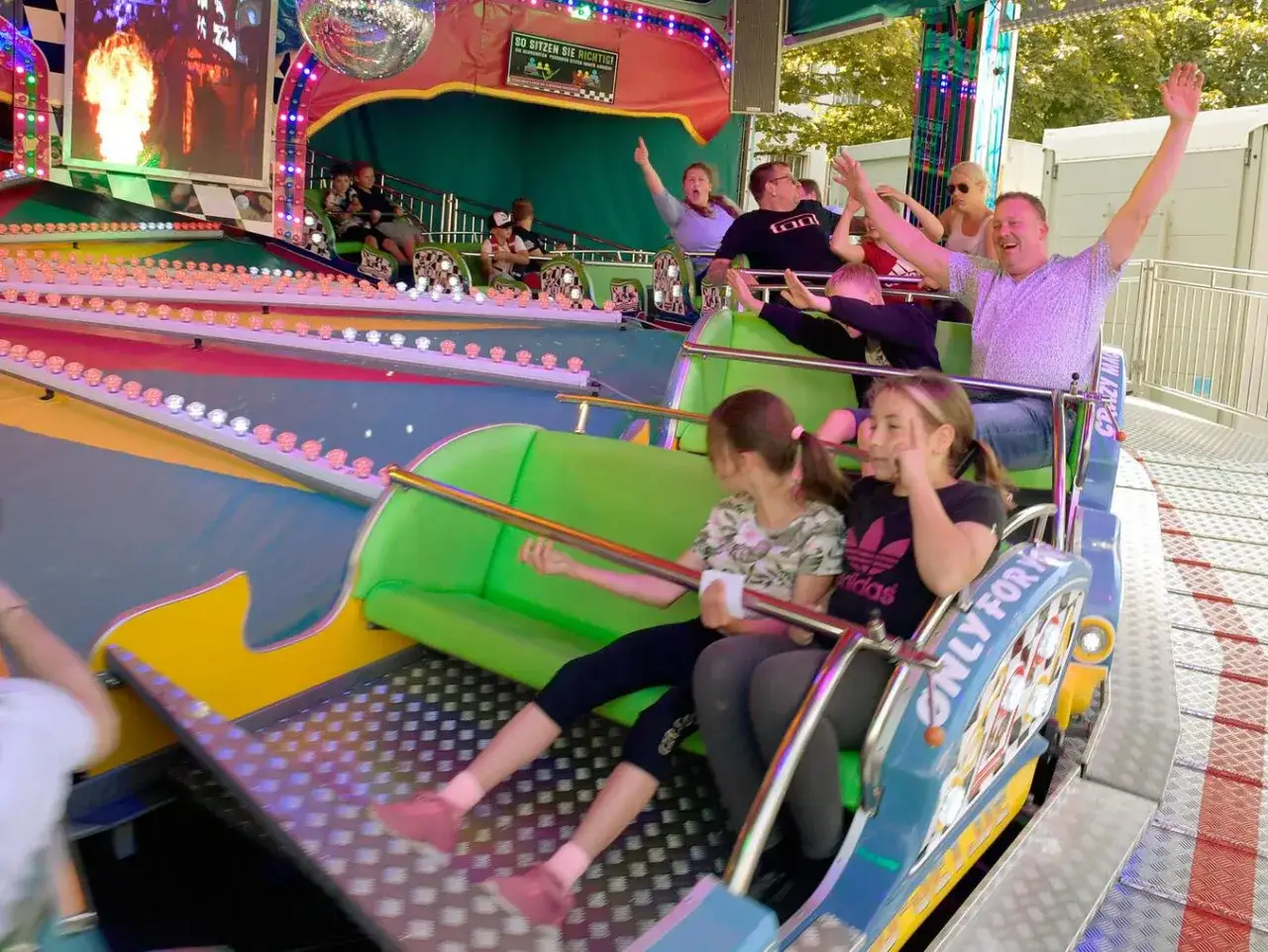 Fr&ouml;hliche Menschen auf einer Kirmes in Gummersbach, die Achterbahn fahren und die Fahrt genie&szlig;en.