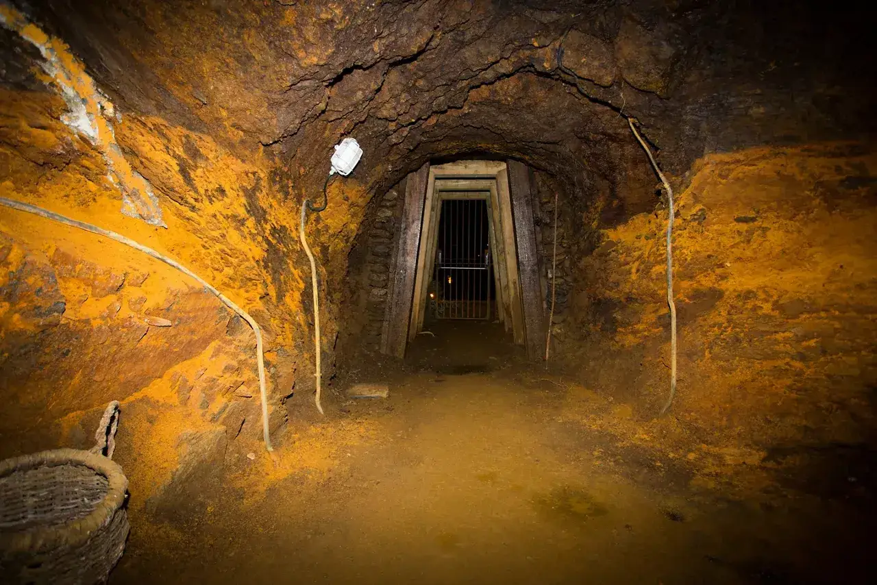 Interior de una mina con paredes ocres y una puerta de rejas al fondo, parte de la ruta del ferro andorra.