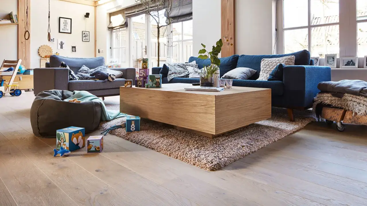 Ein gemütliches Wohnzimmer mit blauen Sofas und einem Holztisch. Welche Farbe passt zu Silber? Hier: warme Holztöne und ein beiger Teppich.