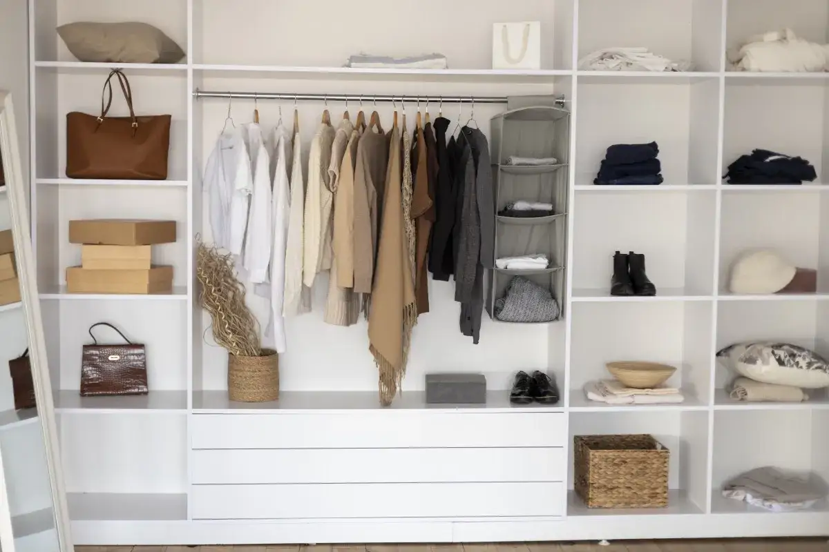 Ideas para como hacer un vestidor en una habitaci&oacute;n barato: estanter&iacute;as blancas, perchas con ropa, bolsos, cajas y accesorios.