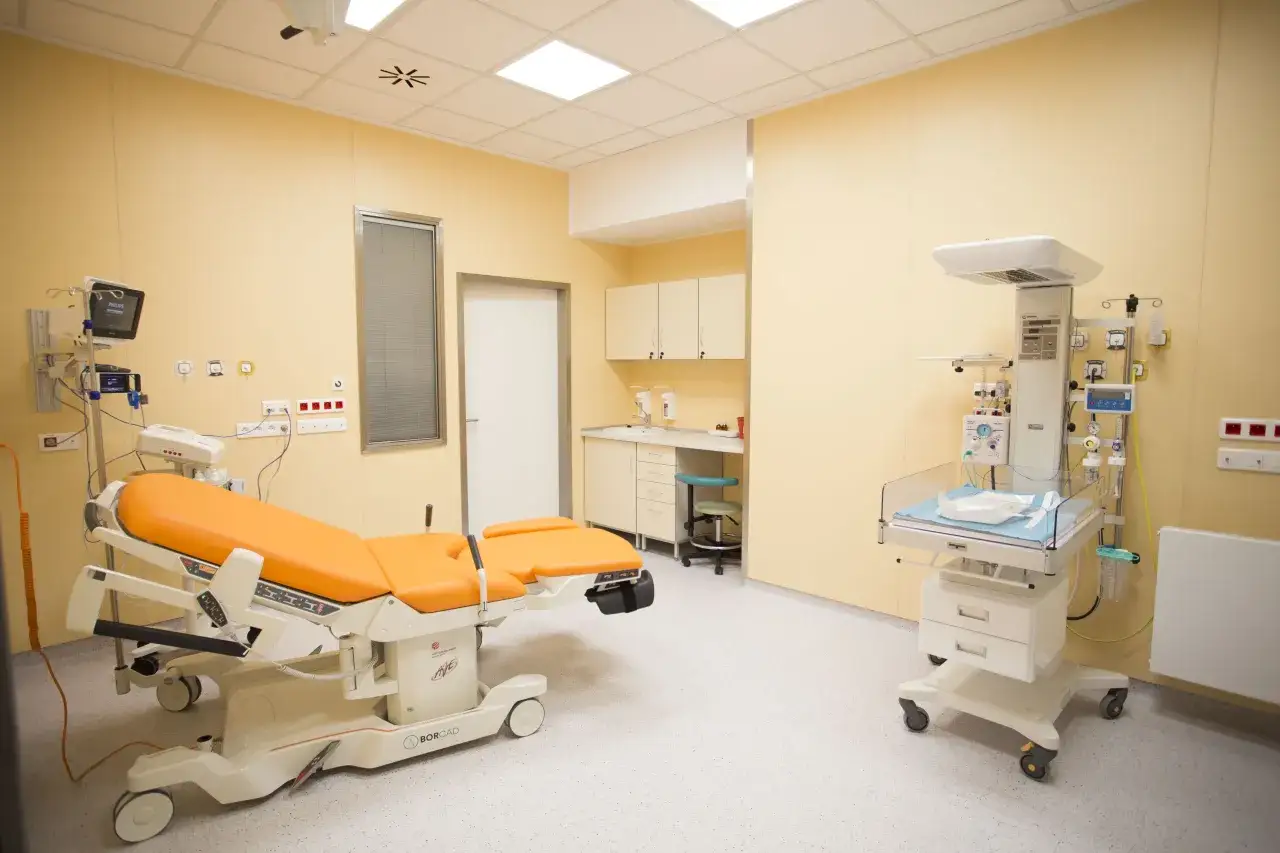 Sala porodowa w szpitalu Żwirki i Wigury. Pomieszczenie wyposażone w nowoczesny fotel porodowy, inkubator i aparaturę medyczną.