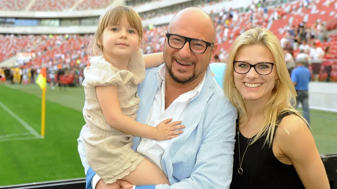 Piotr Gąsowski z córką i partnerką na trybunach stadionu. Uśmiechnięta rodzina kibicuje.