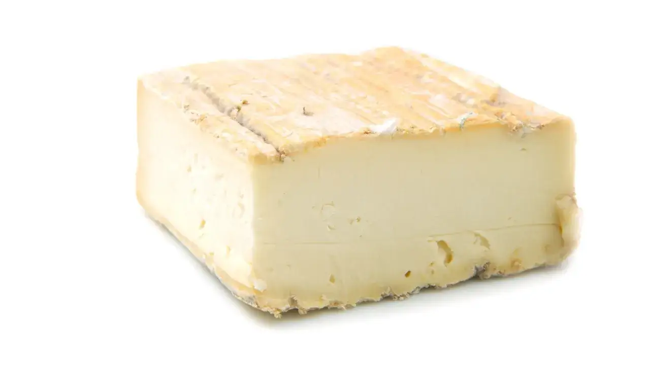 Un trozo de queso Taleggio, con su corteza rústica y su interior cremoso. El queso Taleggio es fuerte, con un sabor intenso y característico.