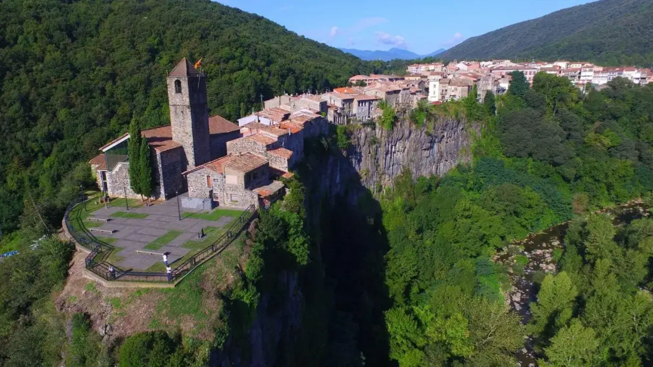 El pueblo de Castellfullit de la Roca se alza espectacularmente sobre un acantilado basáltico, con su iglesia y casas aferradas a la roca.