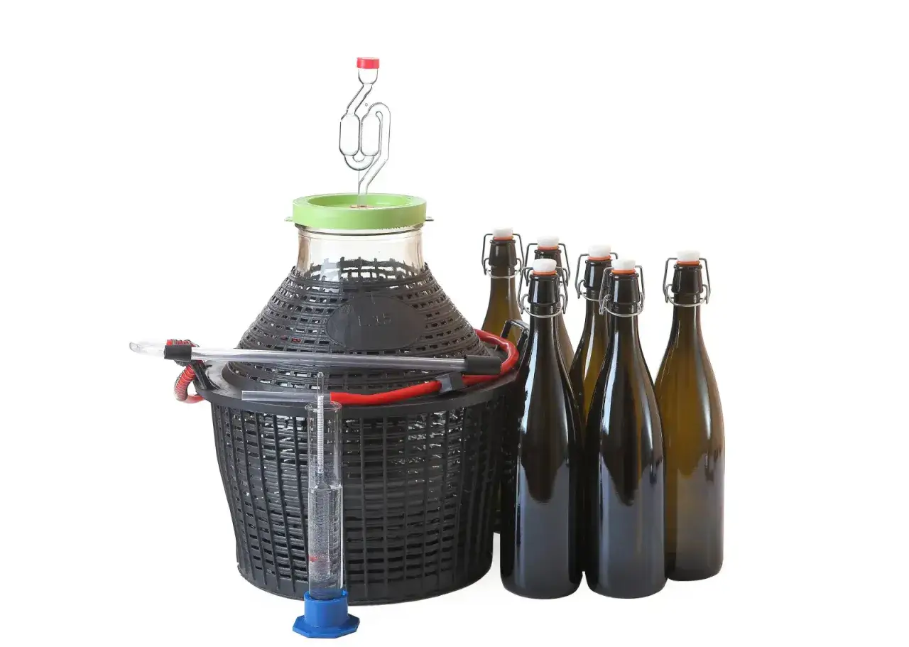 Zestaw do produkcji wina czereśniowego: balon fermentacyjny z rurką fermentacyjną, wężykiem i probówką, a także kilka butelek.