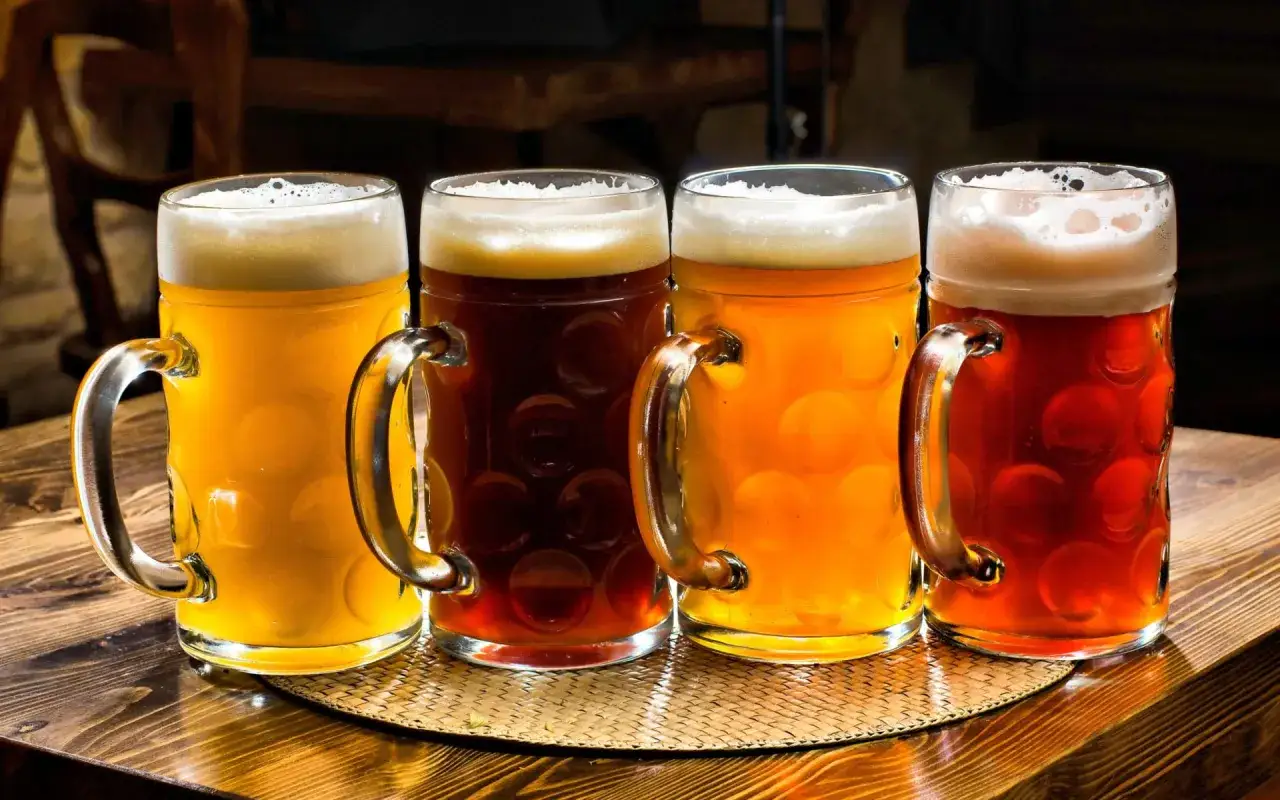 Quattro boccali di birra, tra cui una strong lager ambrata, su un tavolo di legno.