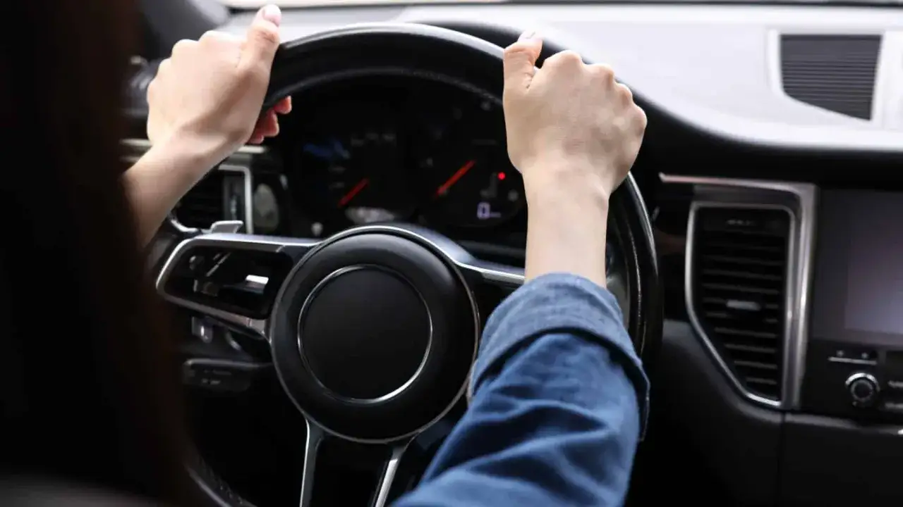 Manos al volante, el coche avanza. La dirección del coche rota suavemente mientras el conductor se concentra en el camino.