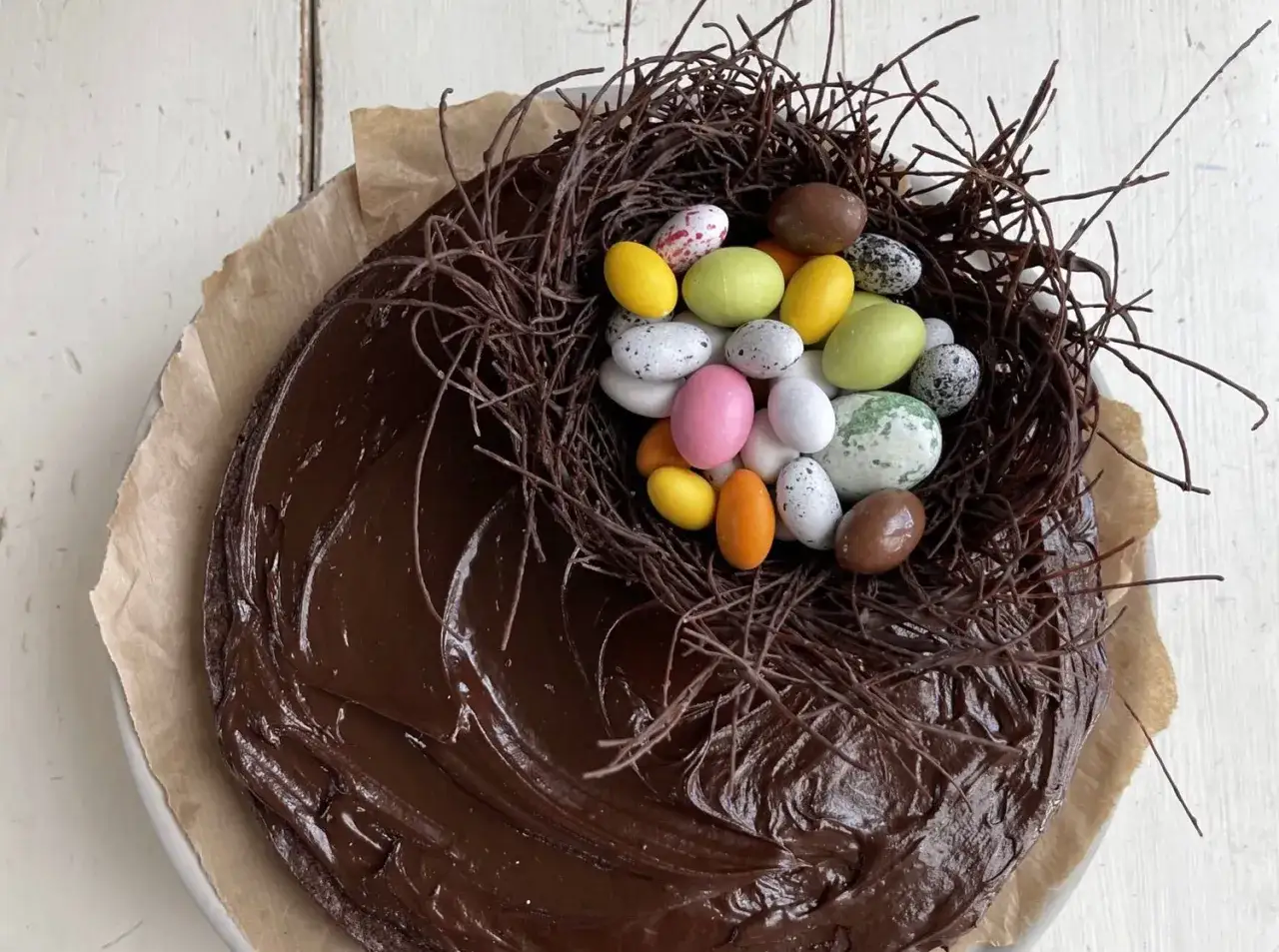 Chokladtårta med ett fågelbo av chokladgrenar och färgglada påskägg. En härlig påsktårta choklad!