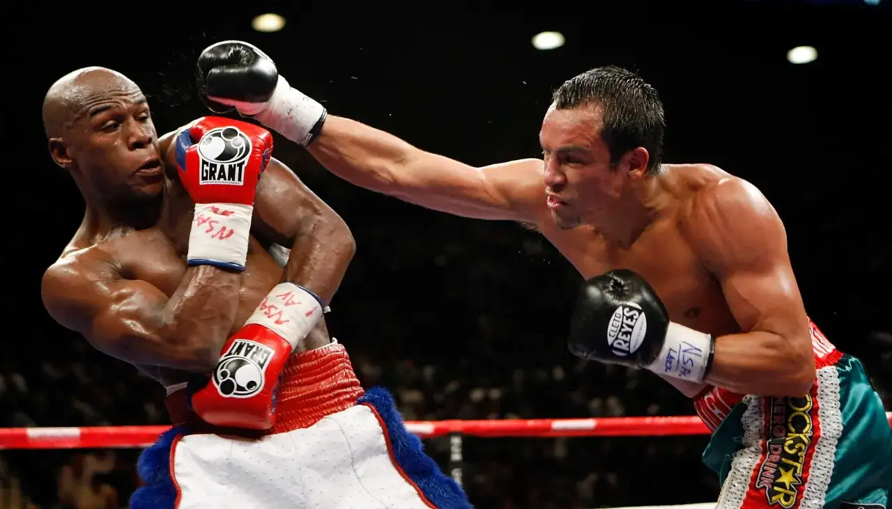 Boxer dodges a punch with a shoulder roll, his opponent's glove narrowly missing his head.