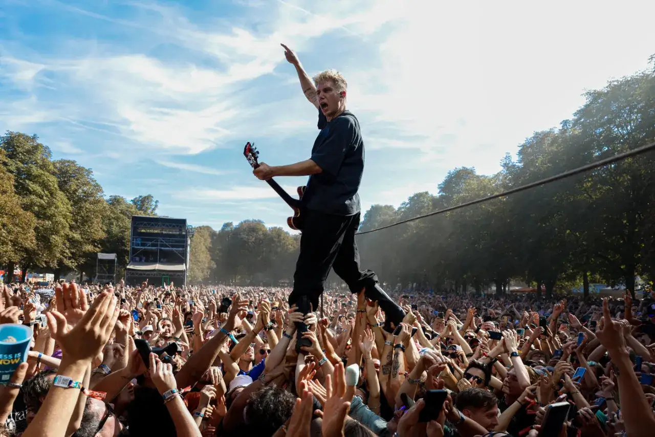 Le chanteur du groupe Last Train, port&eacute; par la foule, joue de la guitare sous un ciel bleu.