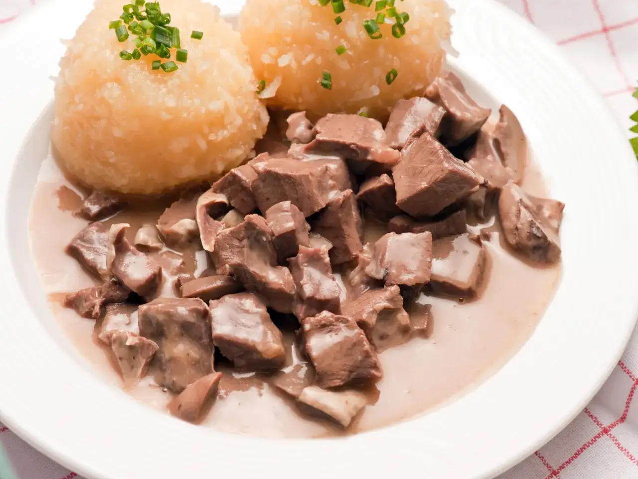 Saure Lunge in cremiger Soße mit Kartoffelklößen, garniert mit Schnittlauch. Ein deftiges Gericht, das an Omas Küche erinnert.