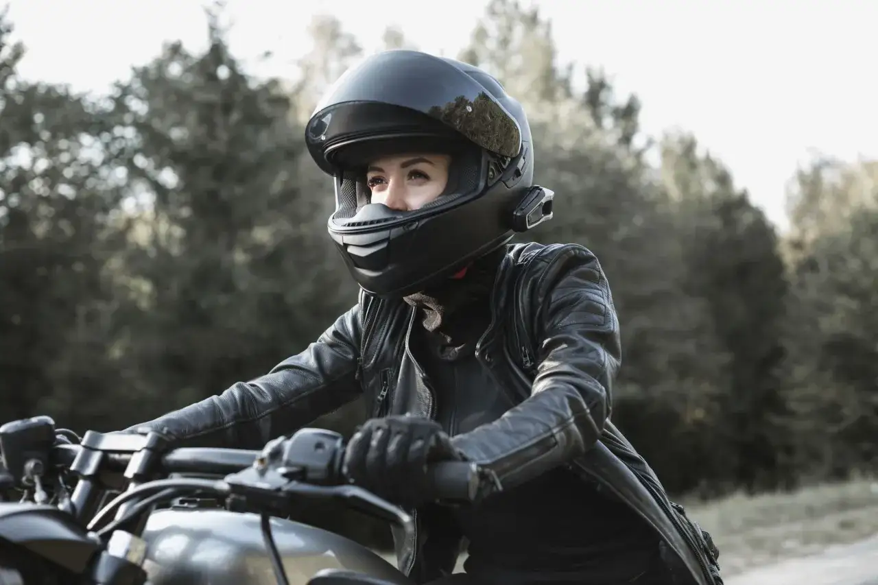 Donna in moto con casco nero, pronta a partire rispettando la normativa casco moto.